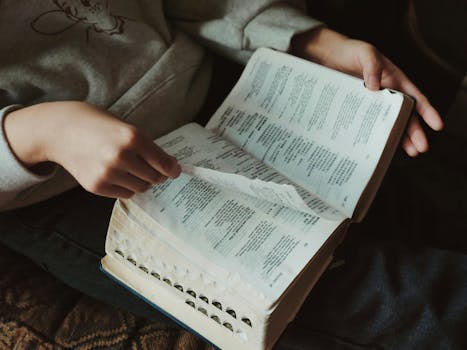 A person flipping through pages of a book, capturing a moment of thoughtful reading indoors.