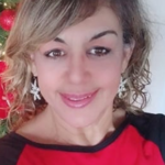Iris Flores stands in a classroom setting, a Bible in hand, illustrating her dual dedication to teaching children and adults the truths of God’s Word