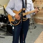 Rafael está al frente de la iglesia tocando su guitarra y cantando con pasión durante un momento especial de adoración, expresando alabanza sincera a través de la música.