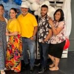 Una familia sonriente de Vision Sinai posa frente a un fondo decorativo del Día del Padre durante el almuerzo de celebración, reflejando el amor y la honra hacia los padres de la congregación.